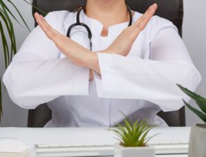 Female medic sitting in a brown leather chair in the office and crossed her arms